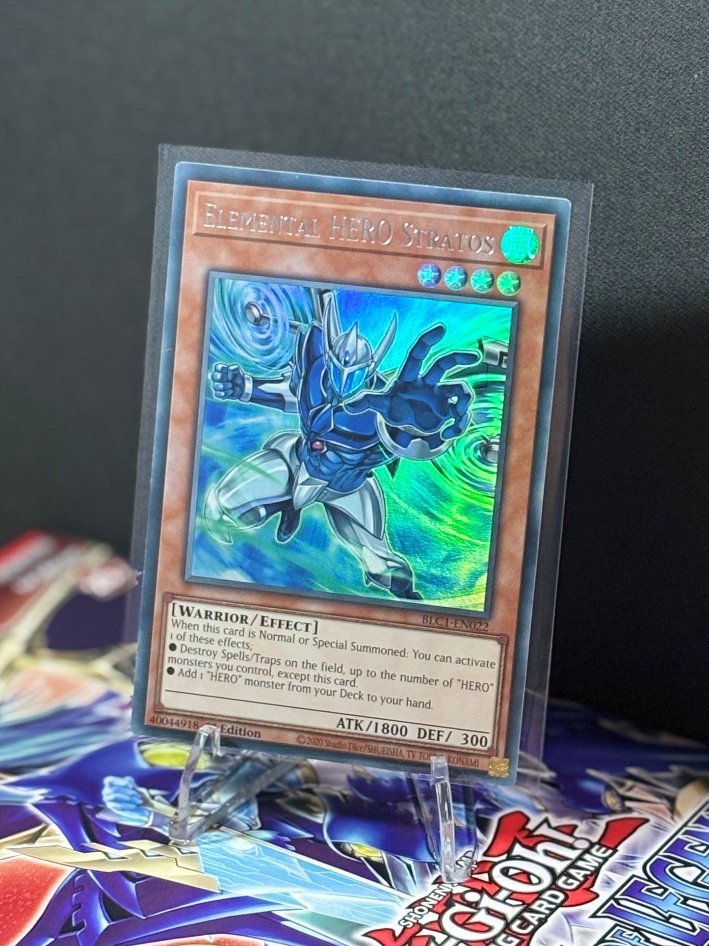 Trading card on top of a trading card game booster pack with a dark background