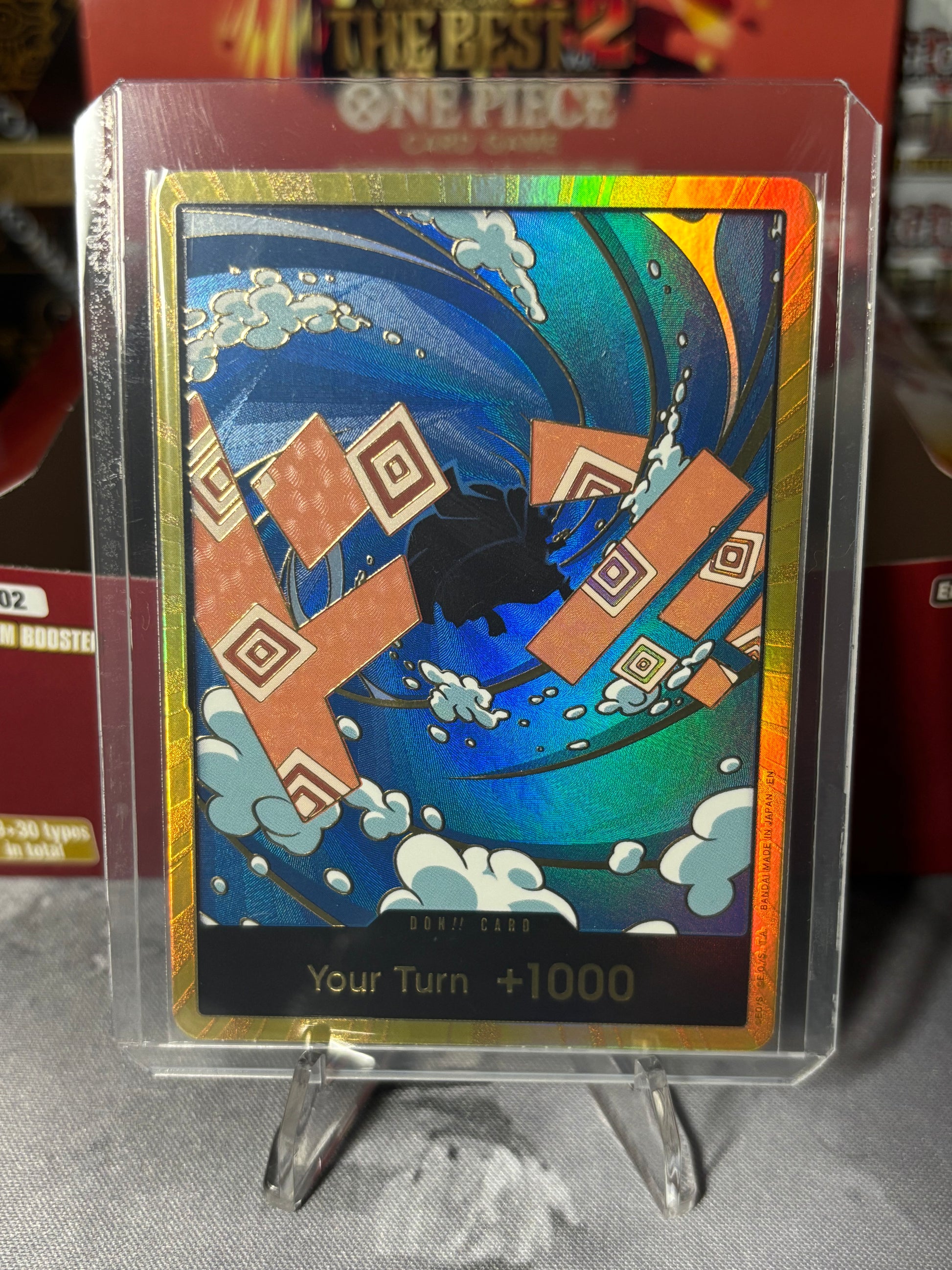 Card with a colorful design featuring a character and text, held in a clear plastic case. Gold Boarder